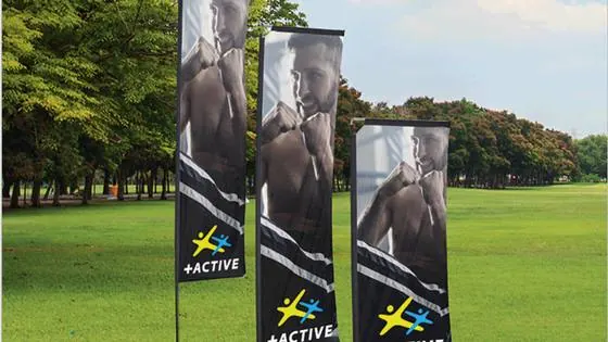 Three double-sided telescopic feather flag banners printed with branding, staked on grass